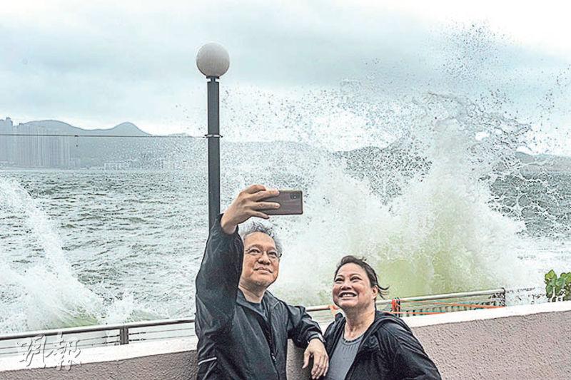 8號風球下，昨早港島杏花邨海旁不停有浪花拍岸，不時比燈柱還高。有市民在岸邊打卡留念，亦有人攀過圍欄到防波堤拍照。早上一度有民安隊員到場勸喻市民遠離岸邊。（馮凱鍵攝）