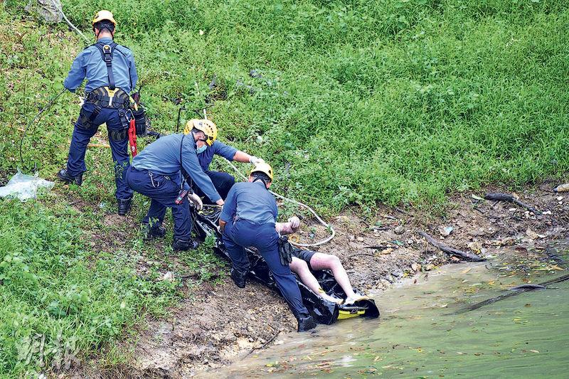 消防在九龍水塘將浮屍撈起，其後用黑膠袋包裹放在「山兜」，再利用繩索經斜坡運回路面。