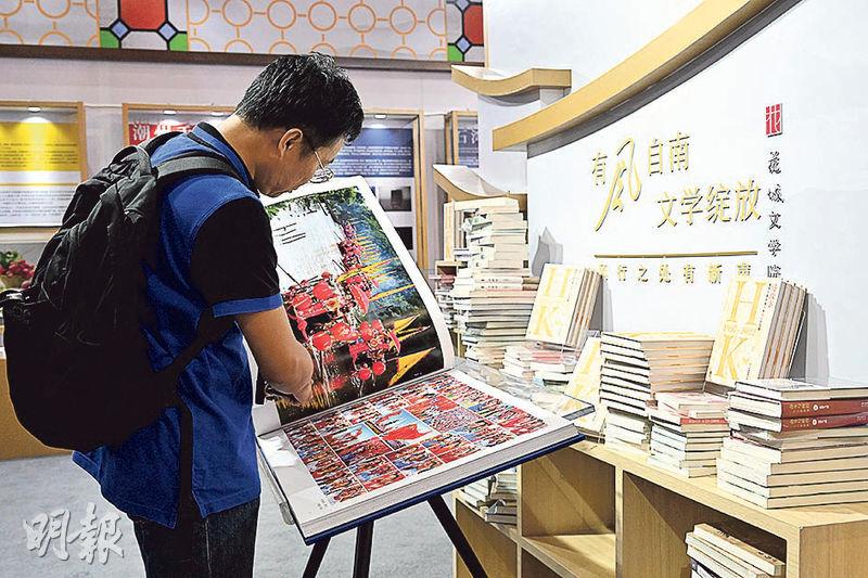 讀者正觀賞書展其中一個攤位「廣東館」的大灣區城市攝影集，內容全為香港、澳門及深圳等大灣區城市的地標風景相片，例如香港維港及澳門大三巴等，售價4.8萬元。由於攝影集採用簡體字，故未知售價是以港元還是人民幣計算。（鄧宗弘攝）