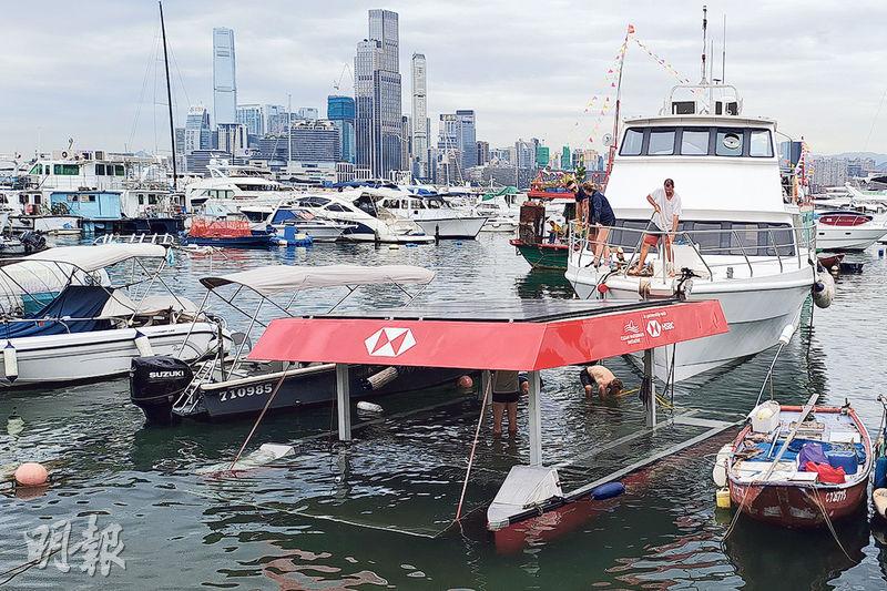 一艘太陽能推動、塑膠廢物收集船於銅鑼灣避風塘入水下沉，只露出頂部及太陽能板（圖）。其後另一艘遊艇靠近，以起重滑輪固定沉船。（林智傑攝）