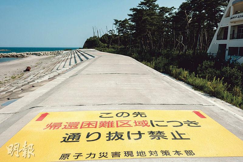 距離福島第一核電站僅4公里的群山海岸，防波堤上「原子力災害現地對策本部」擺放黃色的警告標語，稱該範圍屬「歸還困難區域」，禁止途人前往核電站方向。（賴俊傑攝）