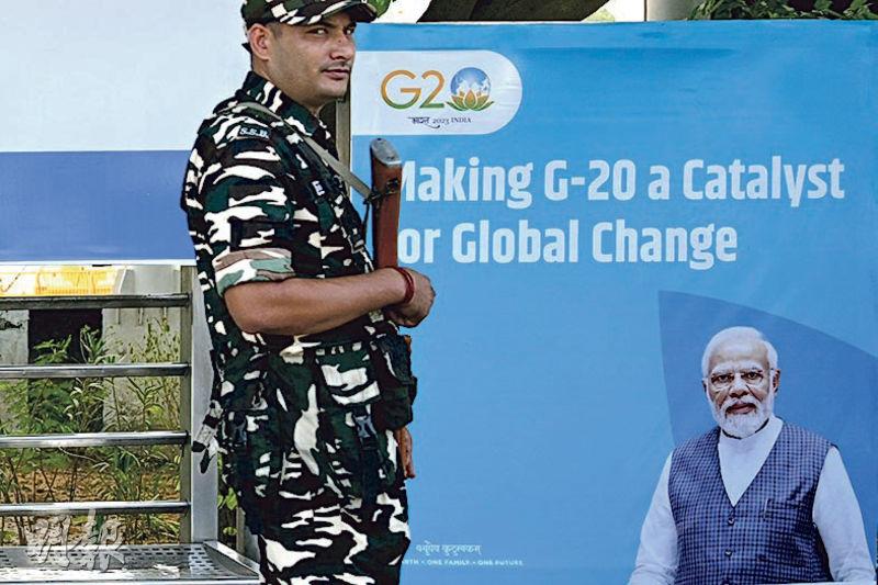 9月4日，G20峰會開幕前夕，在印度新德里，一名安保人員在G20會場附近站崗。會場海報展板上，印着印度總理莫迪的肖像。（法新社）