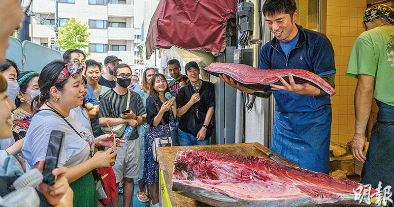 這間位於東京「築地場外市場」的日式餐廳，月初以「解體吞拿魚」作招徠。負責人當日在豐洲市場投得53公斤重的愛媛縣吞拿魚，烈日下在門外帶領群眾，跟着拍子大叫「1、2、1、2」，按節奏切割吞拿魚，並以1500日圓（約80港元）一份售賣刺身。（鄧宗弘攝）