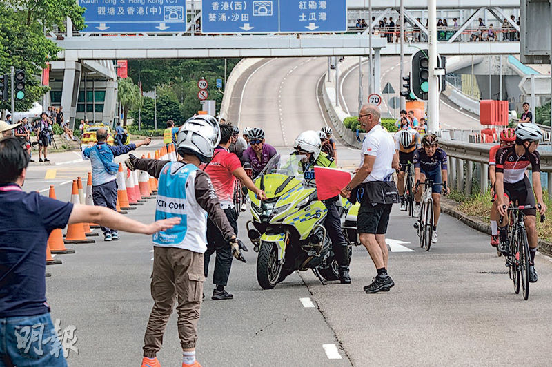 單車連環相撞意外發生後，有工作人員嘗試叫停駛經賽道的選手，但多名車手未理，於傷者兩側駛過。後來工作人員舉出紅旗和有警察到場（圖）。（鄧家烜攝）