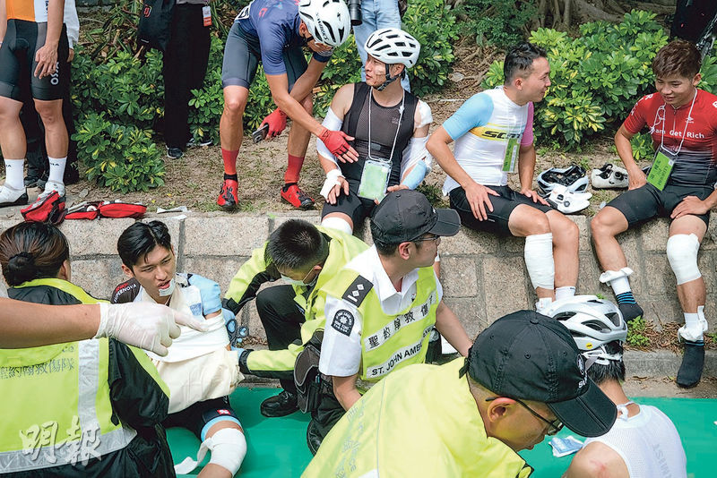 單車節昨早11時許於尖沙嘴麼地道路段發生單車連環相撞意外，事後傷者坐在路邊等候治理，現場所見不少車手的手腳擦傷，救護員分別乘坐約10輛救護車到場為傷者初步治理。（鄧家烜攝）