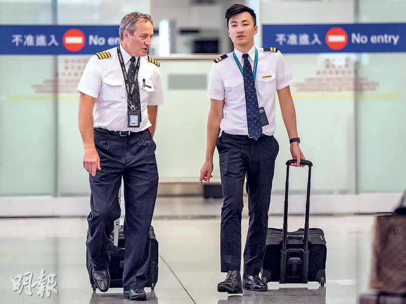 圖為國泰機師在執勤期間途經機場大堂。國泰表示會增加侯命機師數目，令營運更可靠。香港航空機組人員協會指國泰機組人員不足，認為長遠需吸引更多人手，以確保航班服務穩定。（朱安妮攝）