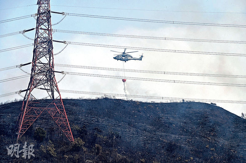 政府飛行服務隊直升機投擲水彈撲救山火，現場靠近電塔。（孫華中攝）