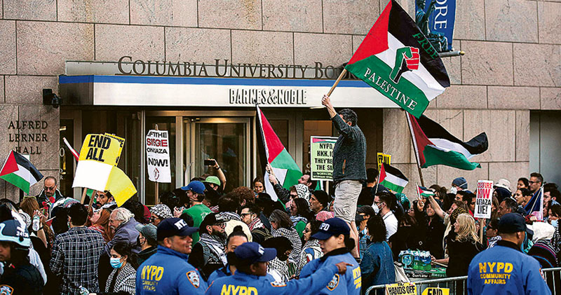 支持巴勒斯坦人士帶着巴人旗幟和標語，上周六在紐約市哥倫比亞大學校園外示威。（法新社）