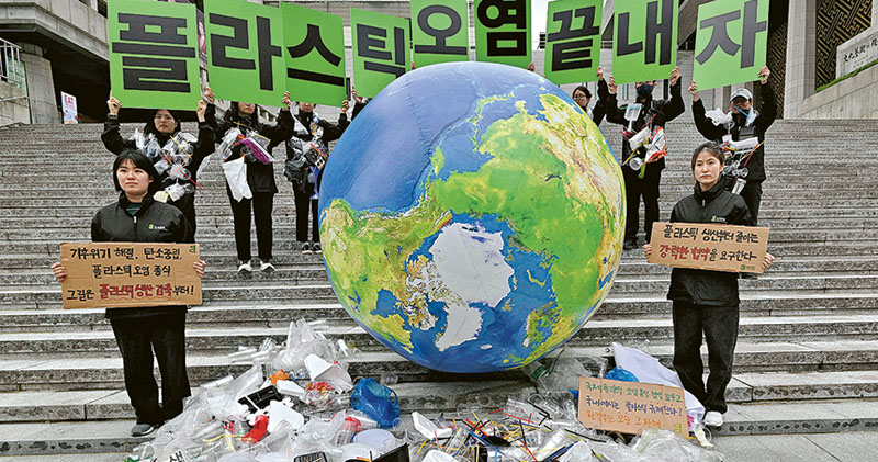 周一為世界地球日，在韓國首爾，有環保人士展示一個堆滿塑膠垃圾的地球圖案氣球，並高舉寫有「讓我們結束塑膠污染」的標語牌，呼籲人們減少使用塑膠。（法新社）