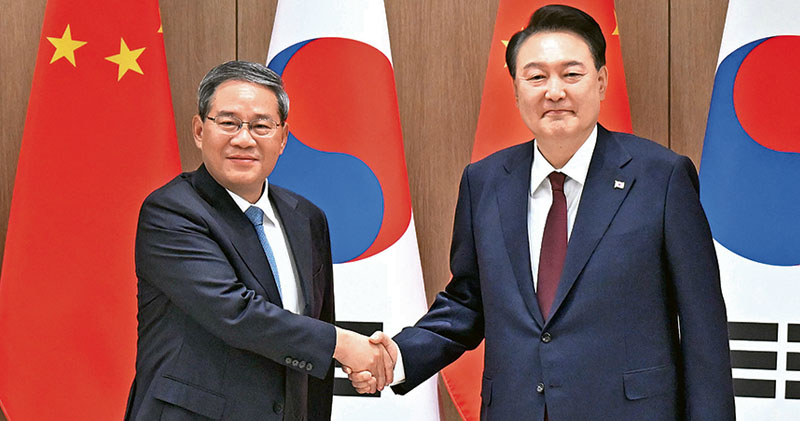 國務院總理李强（左）昨日下午在首爾會見韓國總統尹錫悅（右）。兩人在雙邊會談前握手致意。（新華社）
