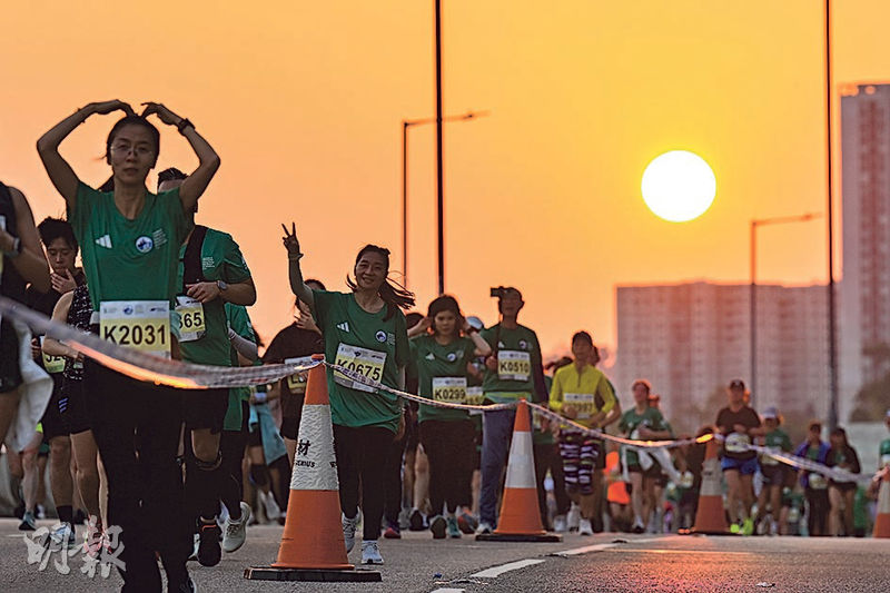 渣馬10公里首場賽事昨早5時半開跑,跑手途經東區走廊時正值日出,有跑手看到鏡頭時擺出心形手勢及舉起「V」字手勢。(盧曼盈攝)