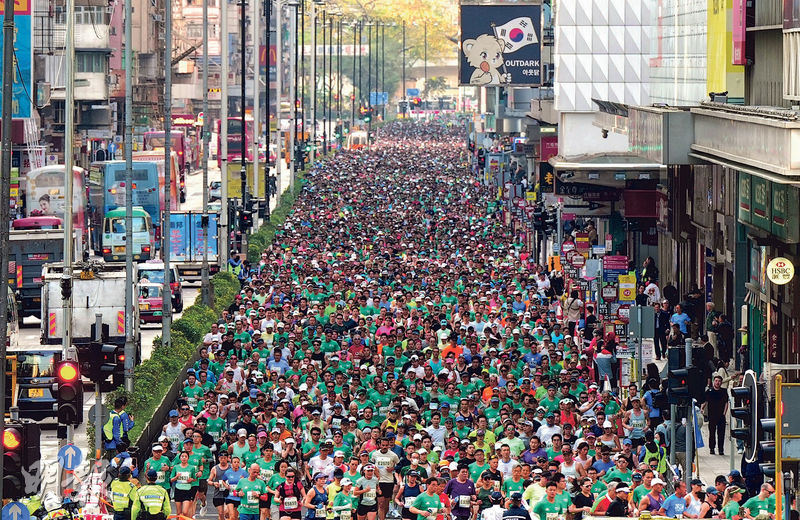 圖為昨日渣打香港馬拉松跑手經過彌敦道,今屆參賽名額有逾7.4萬個,大會稱出席率逾九成,當中包括來自110個國家及地區的非本地跑手參與,佔整體人數25%,為歷年之冠;海外精英跑手數目42名同創新高。大會並宣布來屆賽事明年1月17日舉行。(廖凱霖攝)