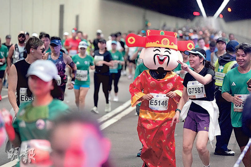 距離農曆新年不足一個月,「財神」昨日提早向跑手及市民拜年,不少跑手見到「財神」都上前「打卡」。(廖凱霖攝)