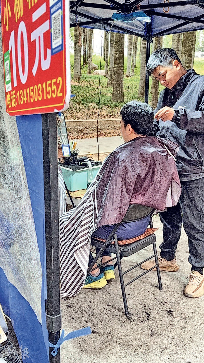 澄海區街頭「十分鐘速剪」理髮攤老闆小楊(右)一天下來多時有逾50顧客,午飯也顧不上吃。(明報記者攝)