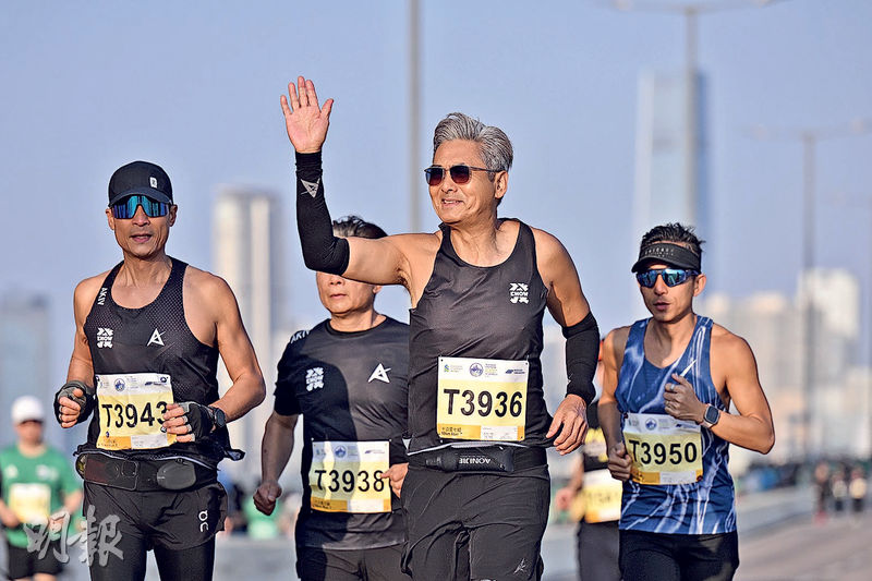 周潤發(前)沿途不停跟市民打招呼,笑稱打到手軟。(盧曼盈攝)